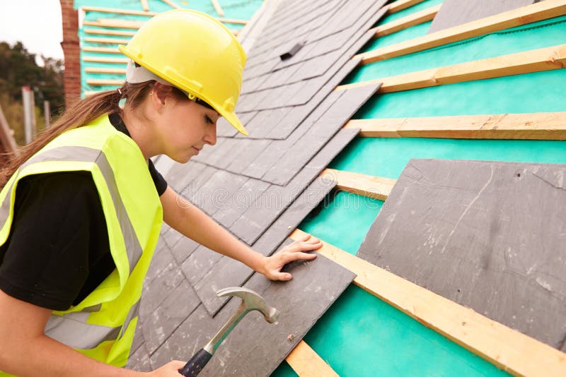 Female Construction Worker On Site Laying Slate Tiles