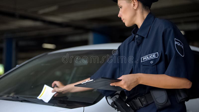 Female cop putting traffic ticket for parking violation on windshield, fine