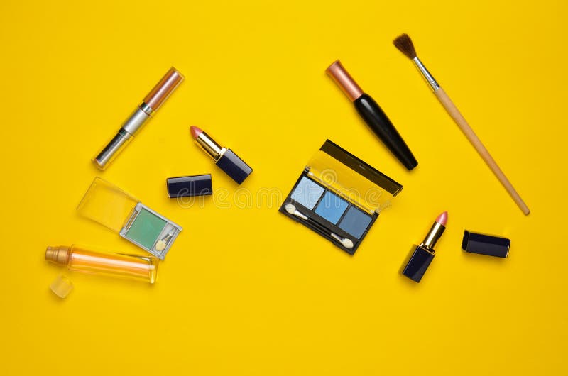 Female cosmetics for make-up layout on a yellow background. Cosmetic shadows, make-up brush, eyeshadow lipstick, perfume bottle. stock photography Female cosmetics for make-up layout on a yellow background. Cosmetic shadows, make-up brush, eyeshadow lipstick, perfume bottle. stock photography
