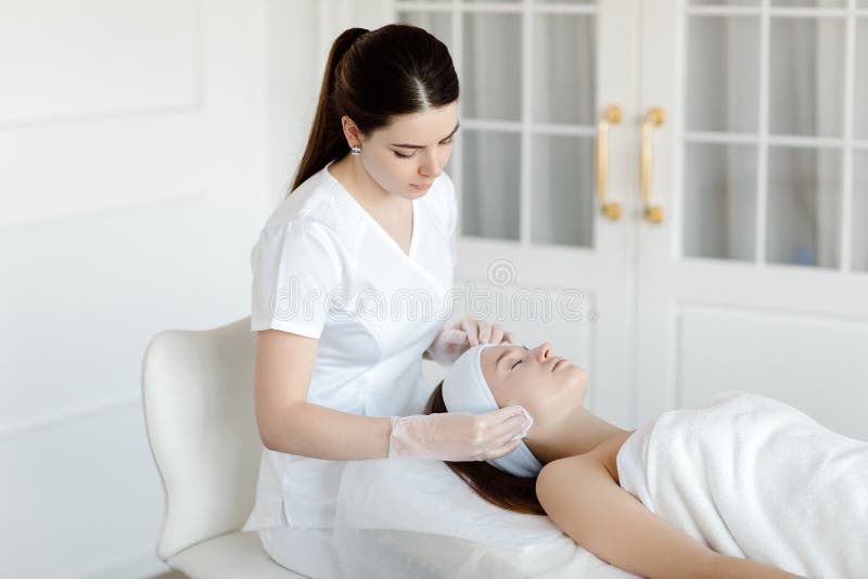 A Female Cosmetologist Makes Facial Procedures For A Client In An