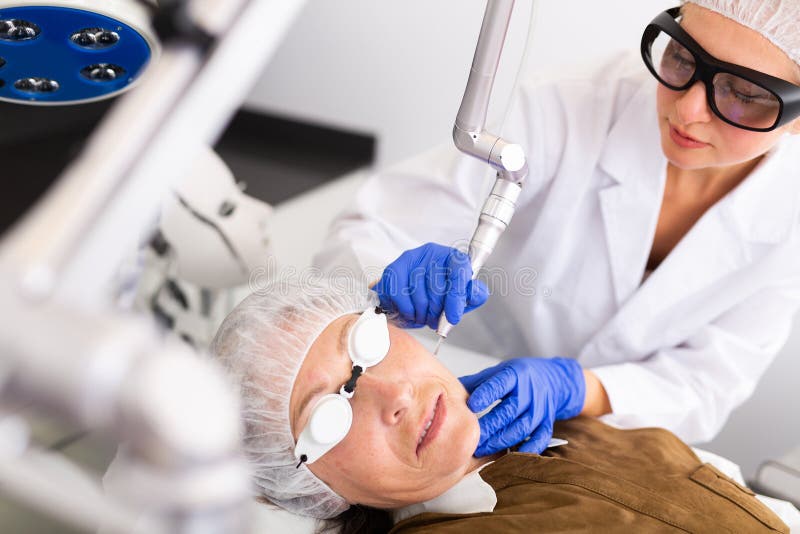 Female Cosmetologist Performing Laser Facial Treatment To Elderly Woman Stock Image Image Of
