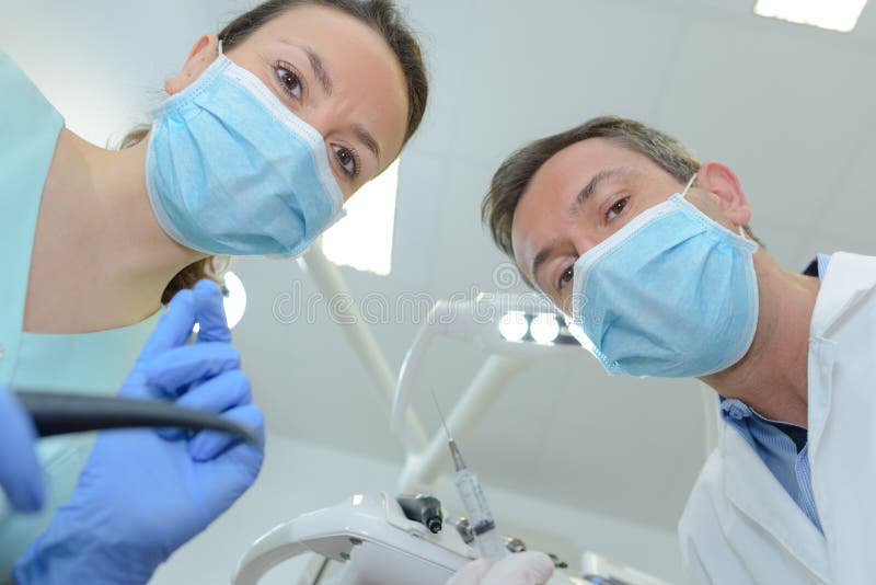 Female Dentist and Assistant Examining Patients Mouth Stock Photo