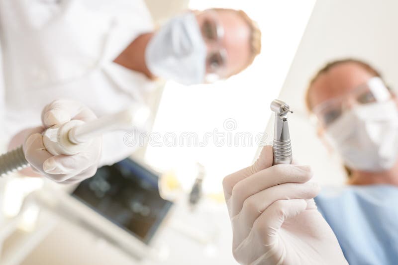 Female dentist and assistant focus on drill stock image