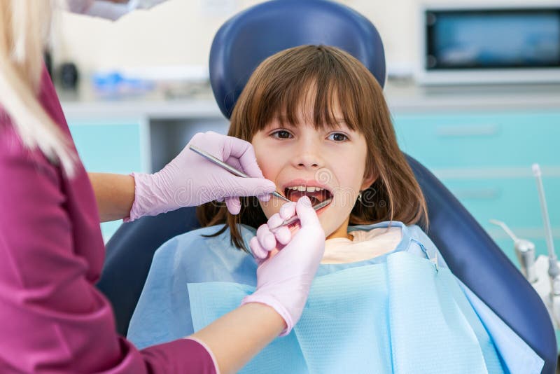 Female dentist in dental office talking with female patient and preparing for treatment. Kids stomatology. In dental office royalty free stock image Female dentist in dental office talking with female patient and preparing for treatment. Kids stomatology. In dental office royalty free stock image