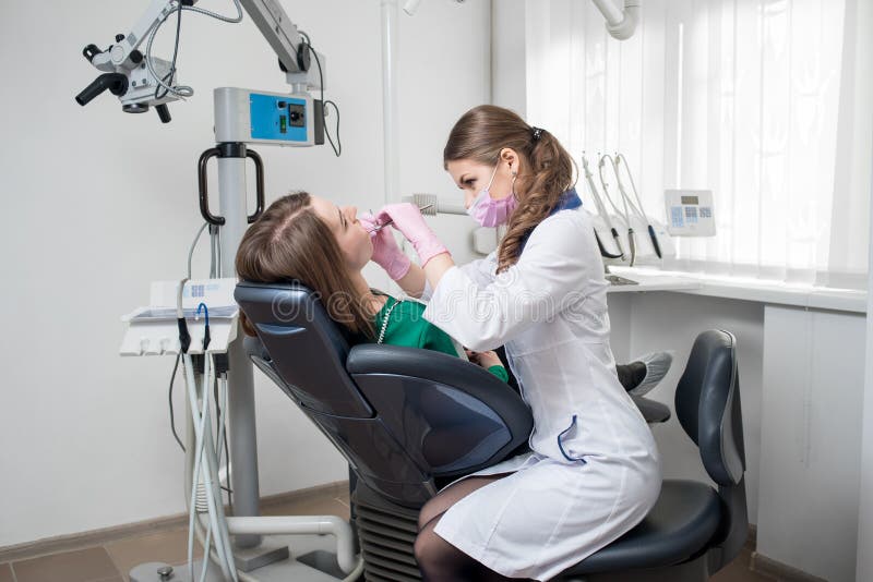 Female dentist with dental tools - mirror and probe checking up patient teeth at dental clinic office stock images Female dentist with dental tools - mirror and probe checking up patient teeth at dental clinic office stock images
