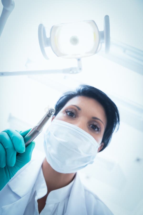 Female dentist in surgical mask holding dental drill stock image Female dentist in surgical mask holding dental drill stock image