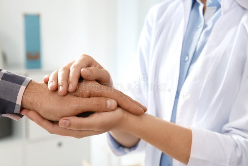 Female doctor comforting man on blurred background, closeup of hands. Help and support concept