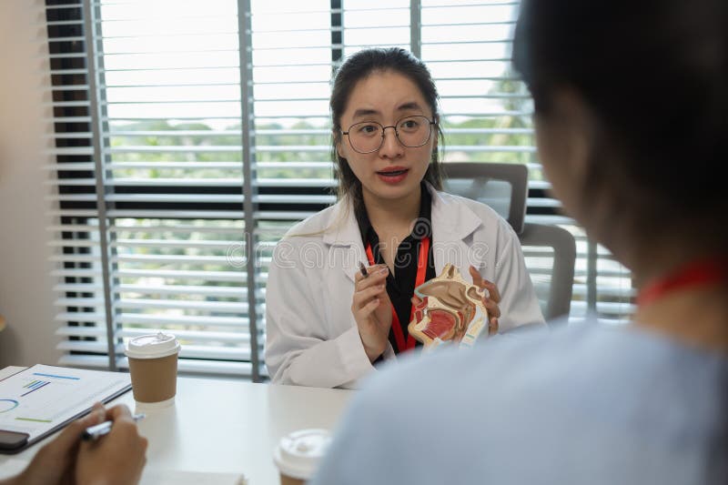 A female doctor is explaining the systems in the human body to two interns, three doctors are meeting to discuss the most stock image