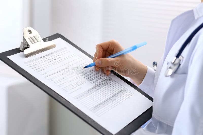 Female doctor filling up medical form on clipboard closeup. Physician finishing up examining his patient in hospital an