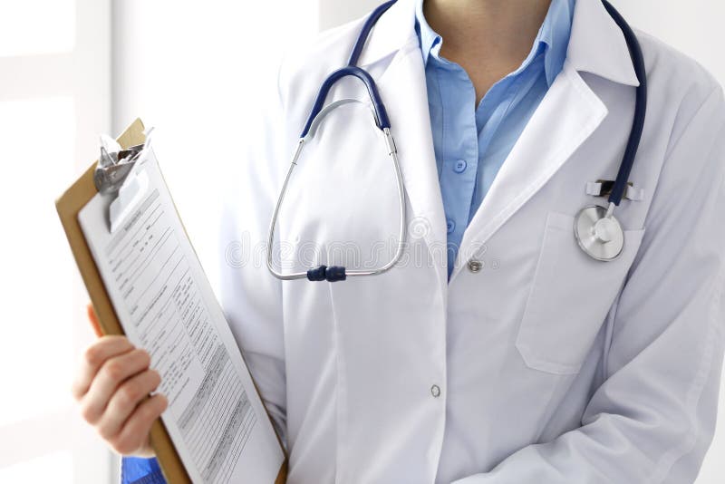 Female doctor filling up medical form on clipboard closeup. Physician finishing up examining his patient in hospital an