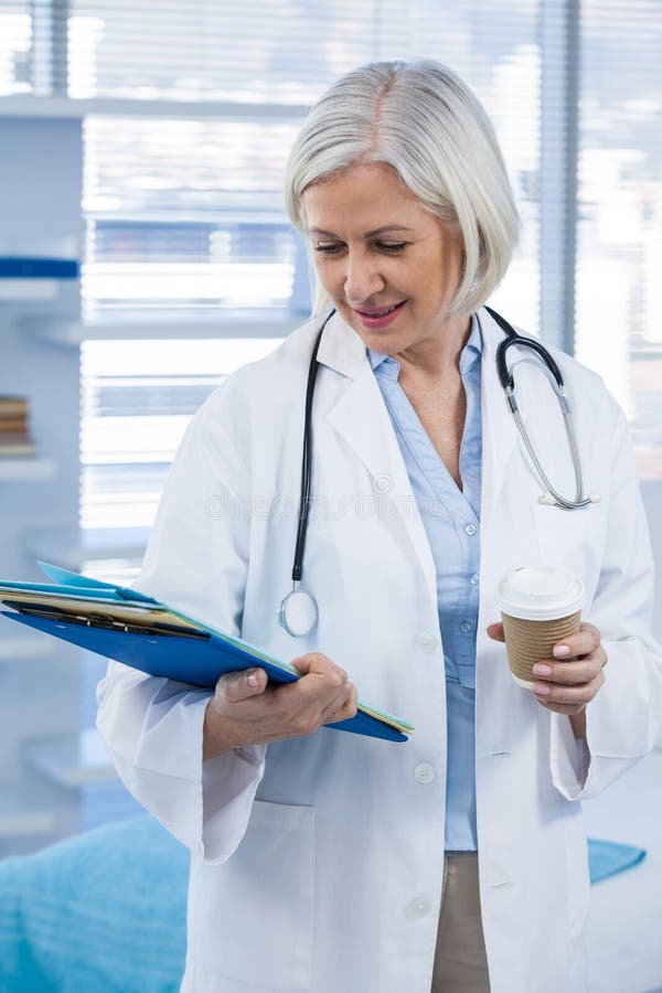 Female doctor holding medical file and coffee cup royalty free stock images Female doctor holding medical file and coffee cup royalty free stock images
