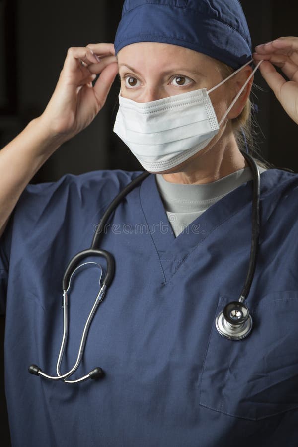Female Doctor or Nurse Putting on Protective Face Mask Stock Image