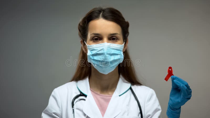 Female doctor in protective mask showing red ribbon, low immunity, HIV AIDS royalty free stock photos Female doctor in protective mask showing red ribbon, low immunity, HIV AIDS royalty free stock photos