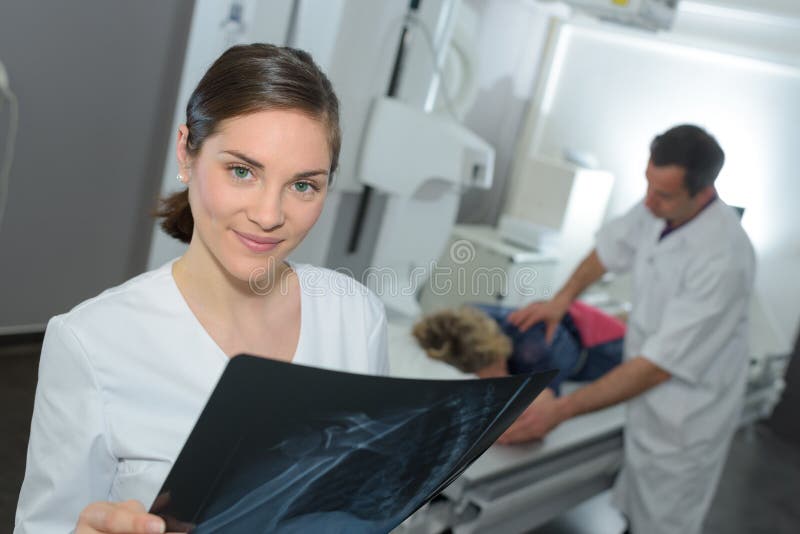 Female doctor with x-ray doctor and patient in background