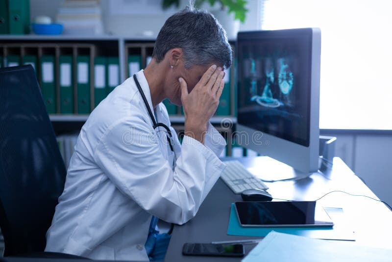 Side view of Caucasian female doctor sitting upset in clinic at hospital