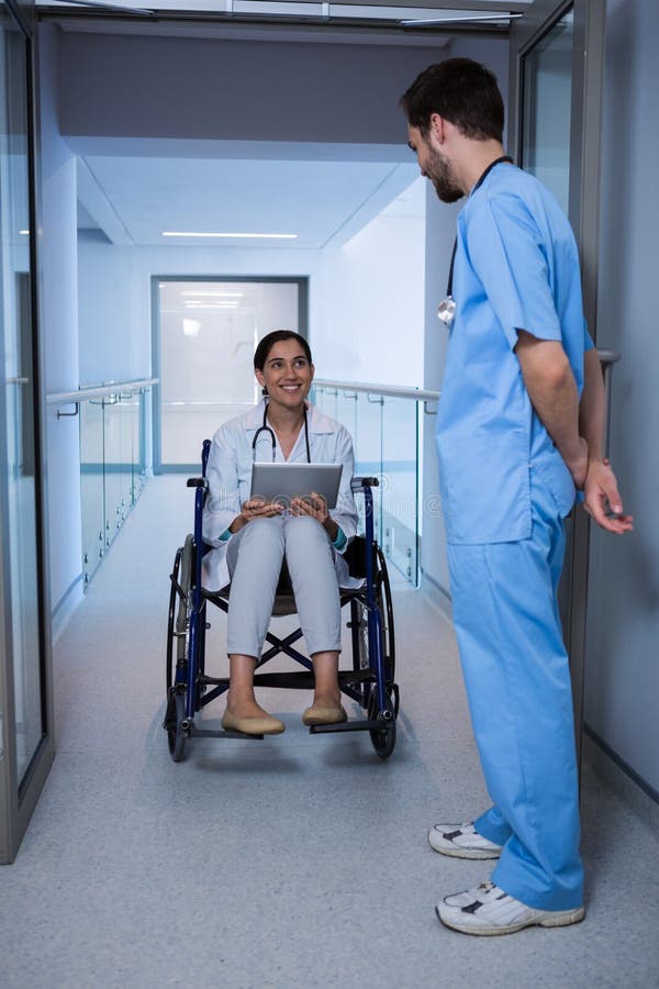 Female Doctor Sitting on Wheelchair and Interacting with Male Nurse ...