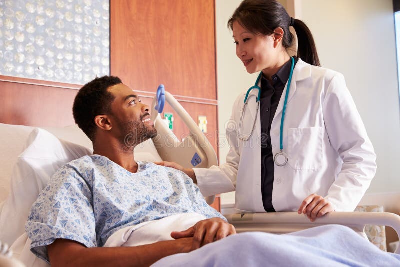 Female Doctor Talking To Male Patient In Hospital Bed