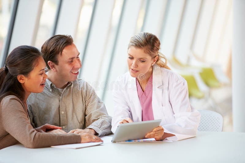 Female Doctor Using Digital Tablet Talking With Patients stock photos