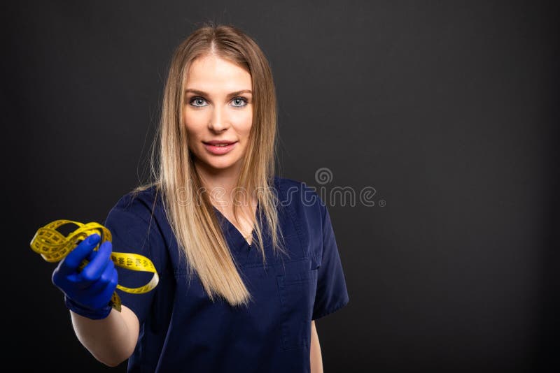 Female doctor wearing scrubs showing measuring tape royalty free stock image