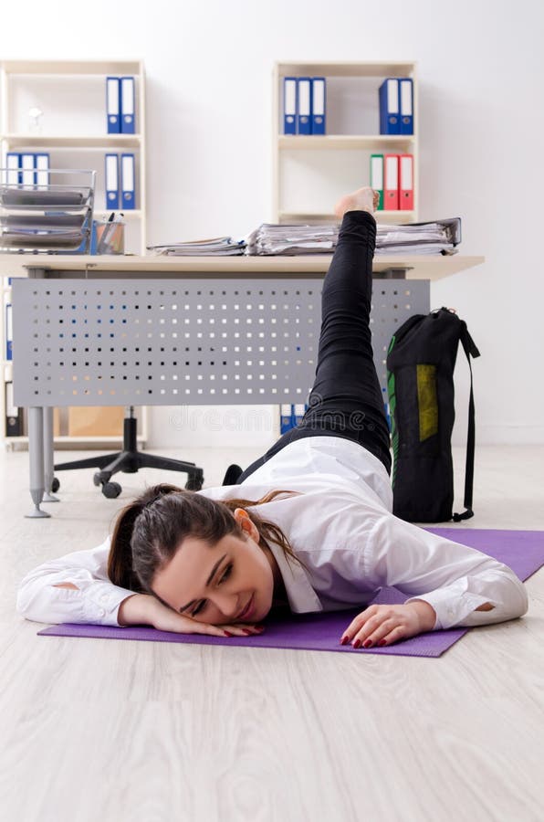 The female employee doing sport exercises in the office stock photo