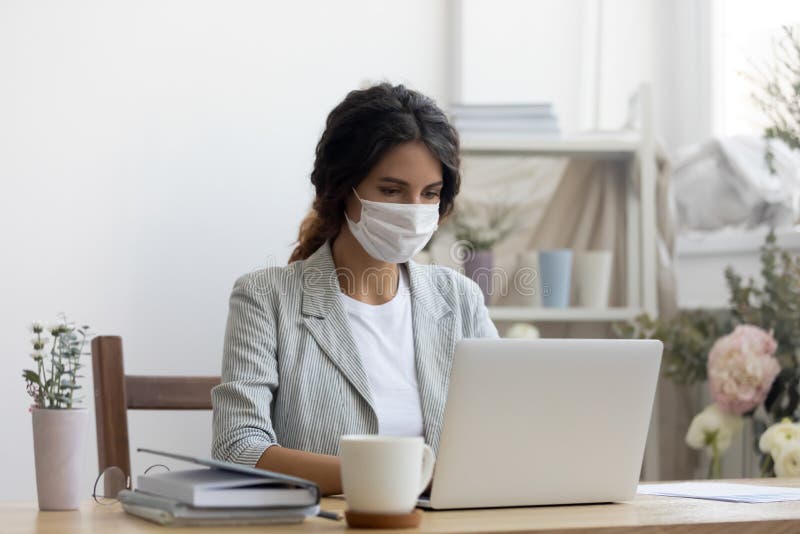 Female employee in medical mask working in office