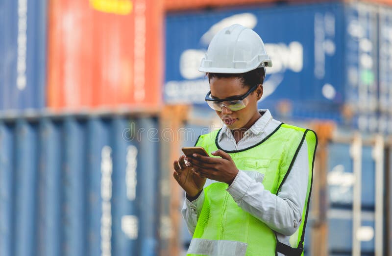 Female engineer in the hard hat uses mobile phone, Industrial worker using mobile smartphone in industry containers cargo stock photography Female engineer in the hard hat uses mobile phone, Industrial worker using mobile smartphone in industry containers cargo stock photography