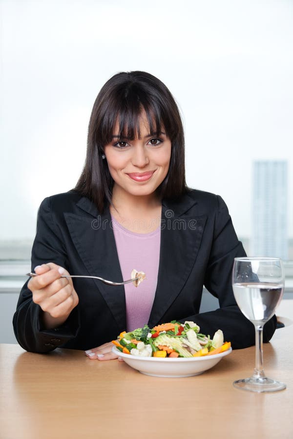 Portrait of smiling female executive having fresh vegetable salad in office. Portrait of smiling female executive having fresh vegetable salad in office