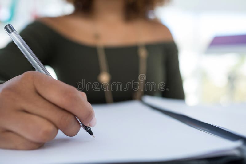 Female Executive Writing on a Document at Desk in the Office Stock