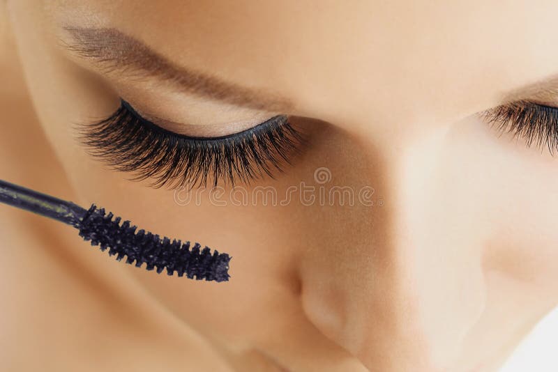 Female eye with extreme long eyelashes and brush of mascara. Make-up, cosmetics, beauty