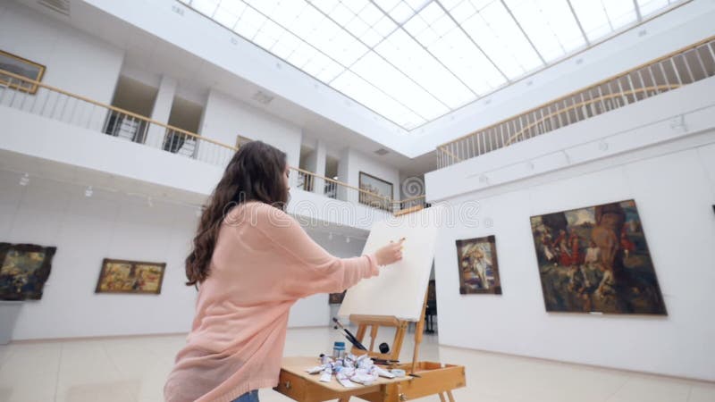 Female fashion artist drawing a picture on easel..