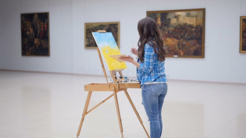 Female fashion painter drawing a picture on easel..