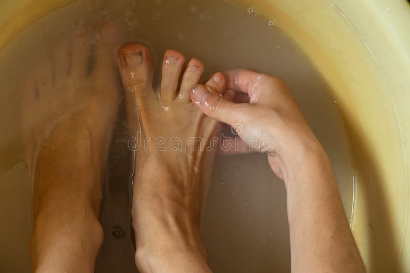 Female feet in soapy water, washing in a plastic bowl