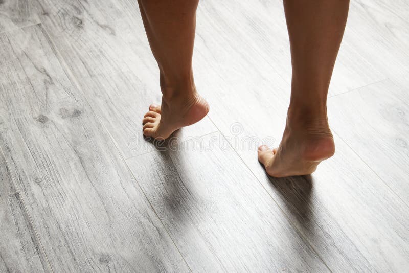 Female Feet Walking Barefoot On Clean Wooden Floor At Home Close Up