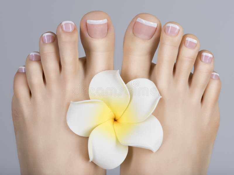 Closeup photo of a female feet with white french pedicure on nails. at spa ...