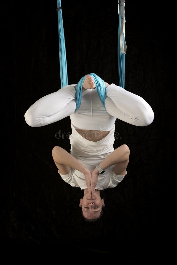 Female fly yoga instructor hangs on hammock in the lotus position upside down. Aerial anti-gravity yoga royalty free stock images