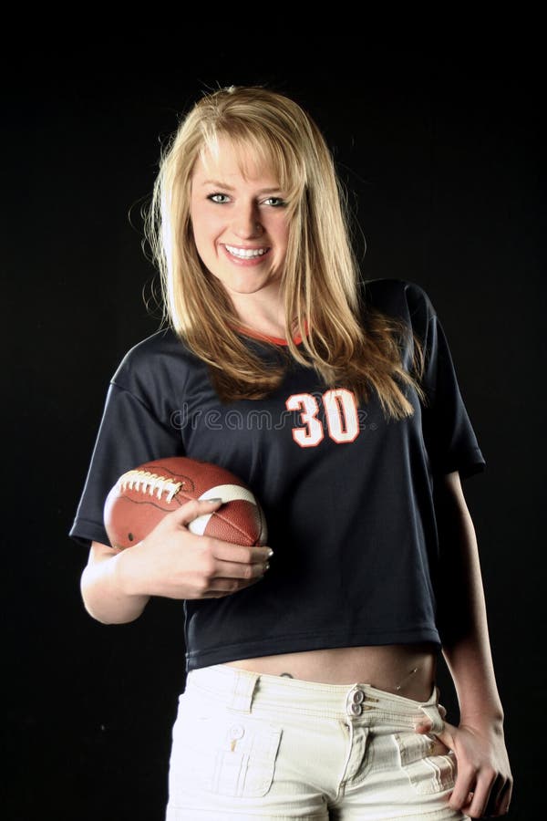 A young blonde female holds a football. A young blonde female holds a football.