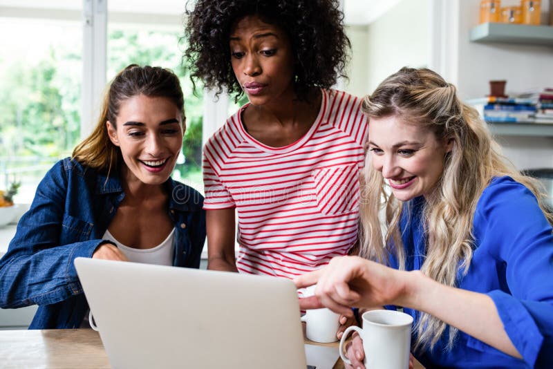 Female friends smiling while looking in laptop stock image Female friends smiling while looking in laptop stock image