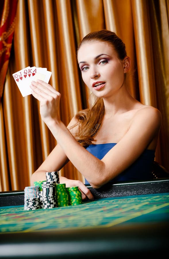 Female gambler at the poker table with cards and chips