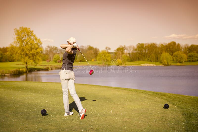 Female golf player teeing off.