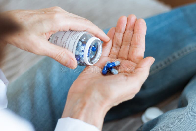 Female hand close up holding a medicine, elderly woman hands with pill on spilling pills out of bottle