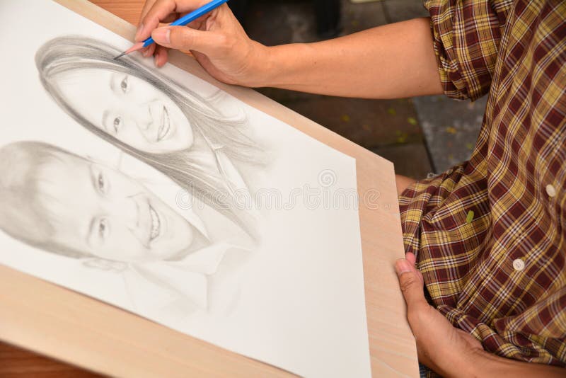 Female hand drawing man and woman smiling with pencil. stock photo Female hand drawing man and woman smiling with pencil. stock photo
