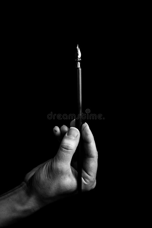 Female hand elegantly holding an ink pen with a metal tip close-up on a black background. classic fountain pen isolated macro