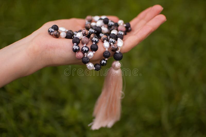 Female Hand Holding a Buddhist Japa Mala Made from 108 Natural Stones Beads  for Meditation on Green Grass Background Stock Image - Image of knotted,  healing: 192600239