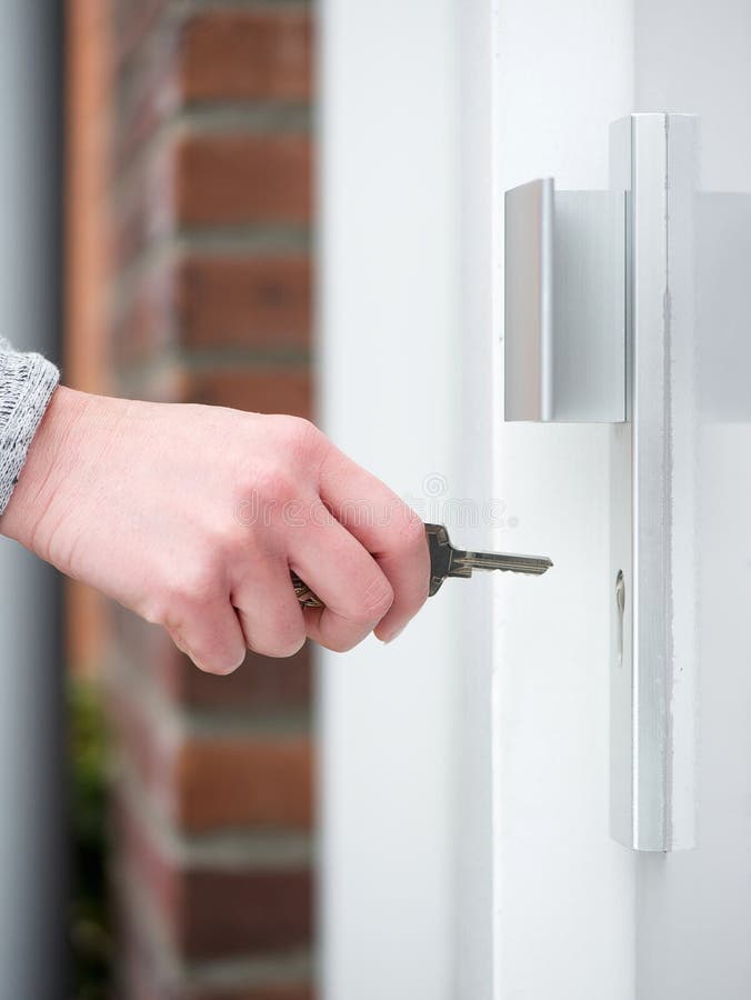 Female hand holding key to insert in door lock