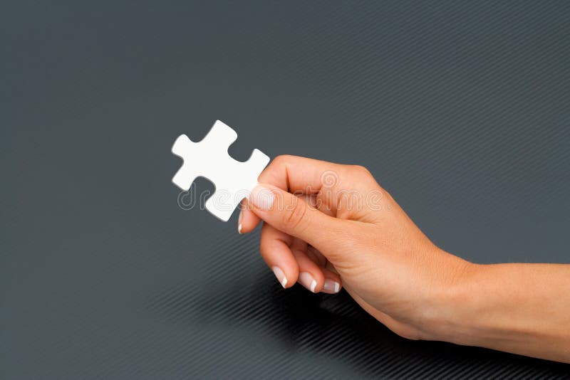 Female hand holding puzzle piece.