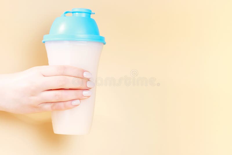 Female Hand Holds Shaker with Protein Shake on Brown Background, Copy