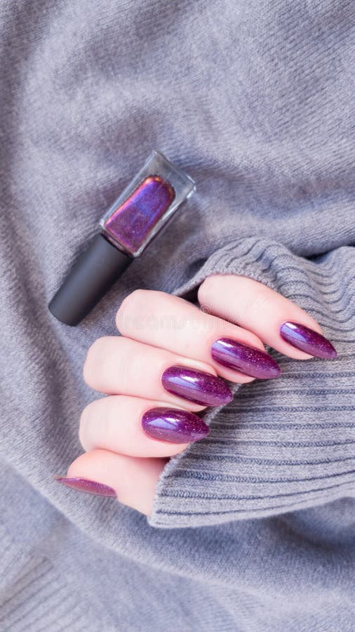 Female hand with long nails holds a bottle with a bordo nail polish. Female hand with long nails holds a bottle with a bordo nail polish