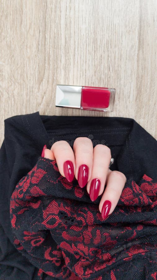 Female hand with long nails and a bottle with red nail polish. Female hand with long nails and a bottle with red nail polish