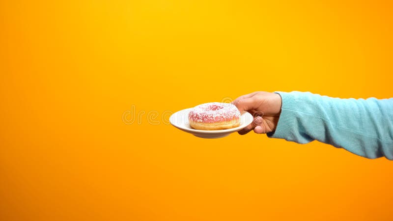 Female hand showing sweet donut, inviting customers to confectionary store stock photography Female hand showing sweet donut, inviting customers to confectionary store stock photography
