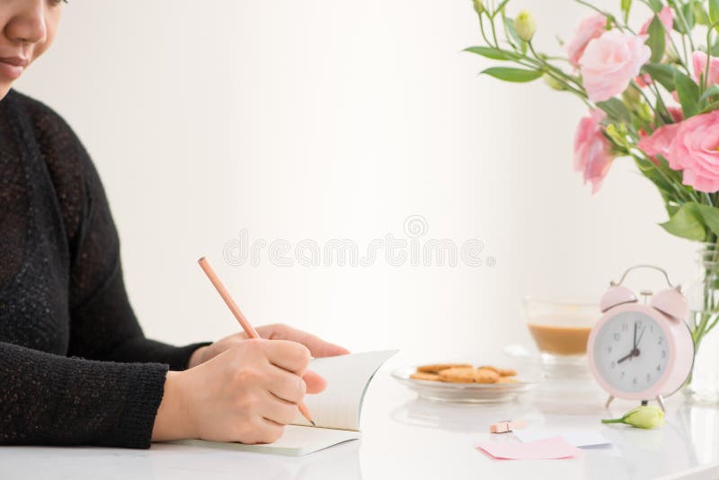 Female hand writing in a notebook at the desk, top view. On the stock images Female hand writing in a notebook at the desk, top view. On the stock images